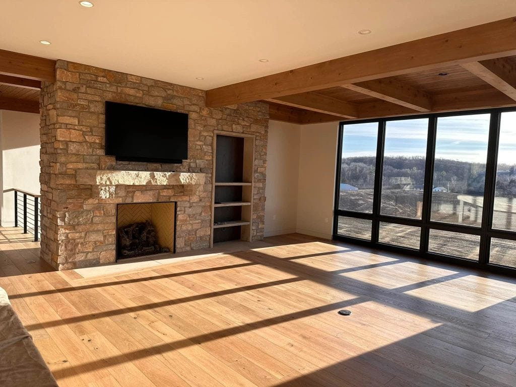Modern living room with large windows and stone fireplace, showcasing professional interior painting and decorating services by Hi-Tech Painting and Decorating. Bright, spacious, and stylish home inte.