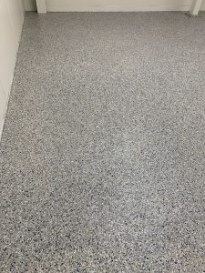 Durable epoxy coating on garage floor with a speckled finish, providing a sleek and protective surface for residential or commercial garages.