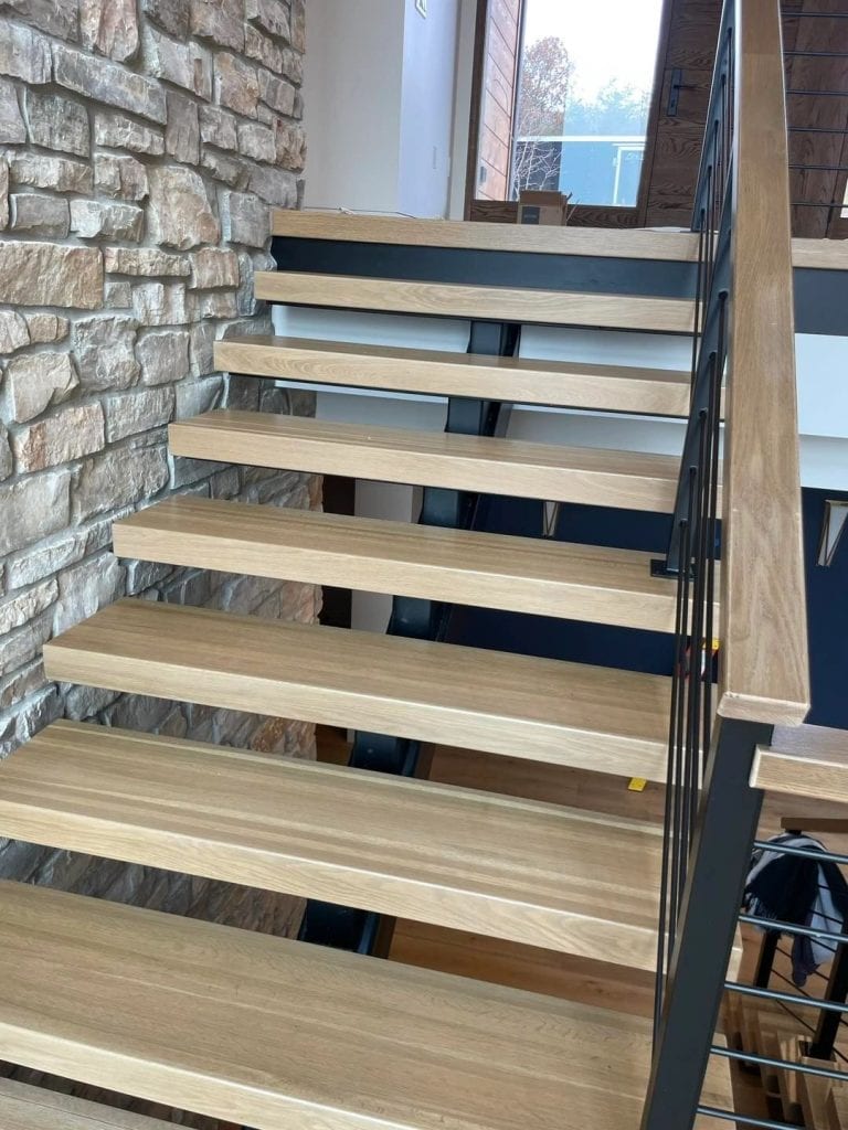 Elegant staircase featuring natural wood treads and sleek black metal balustrade, ideal for contemporary home decor.