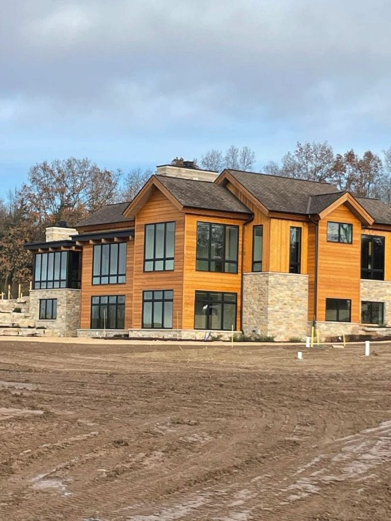 Beautiful contemporary home featuring natural wood siding, expansive windows, and stone details, showcasing expert exterior painting and decorating by Hi-Tech Painting and Decorating.