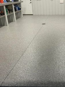 Durable epoxy-coated garage floor with a smooth, speckled finish, showcasing professional flooring installation by Hi-Tech Painting and Decorating.