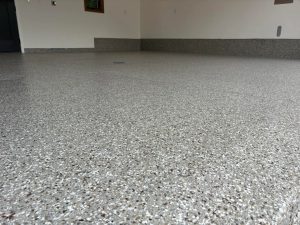 Epoxy garage floor coating applied by Hi-Tech Painting and Decorating, showcasing a durable, polished finish with a speckled pattern for enhanced aesthetics and longevity.