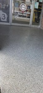 Durable epoxy floor coating applied to commercial space entrance, enhancing appearance and safety with a sleek, textured finish.