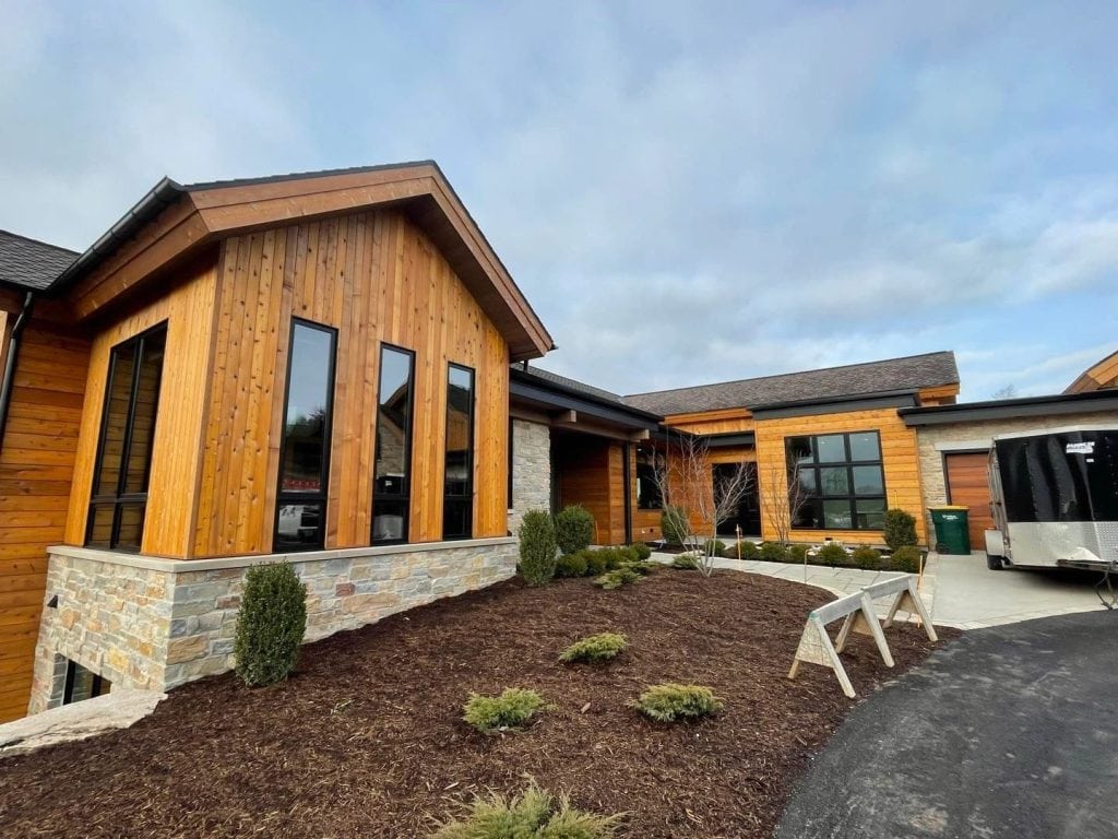 Contemporary wooden house with large windows, landscaped garden, and modern exterior design, showcasing professional painting and decorating work by Hi-Tech Painting and Decorating.