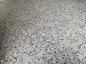 Polished concrete floor with a speckled, decorative finish, showcasing high-quality surface preparation and durable coating. Ideal for commercial and residential spaces seeking a modern, sleek look.