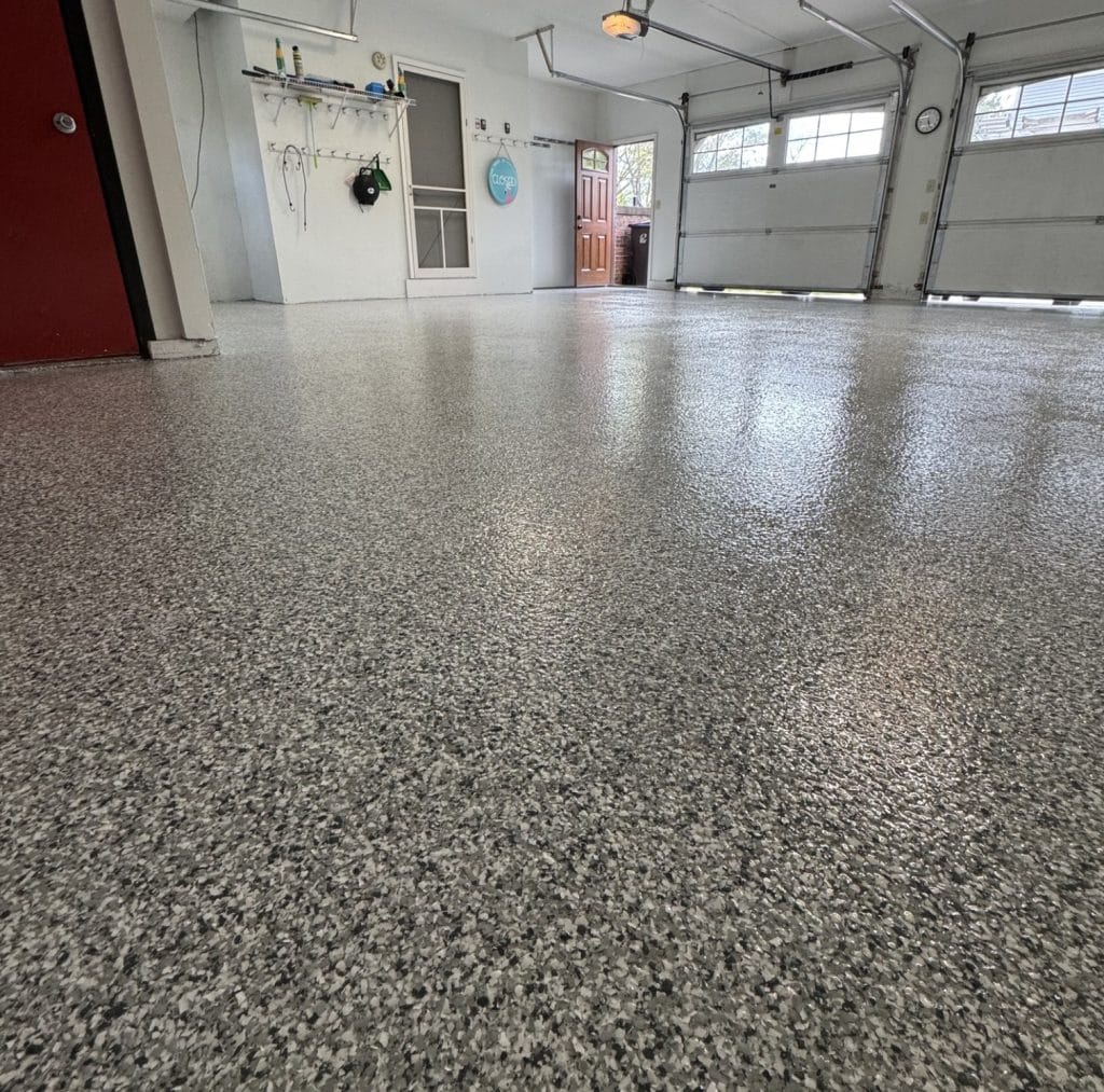 Durable epoxy-coated garage floor with a speckled finish, showcasing professional painting and decorating services by Hi-Tech Painting and Decorating.
